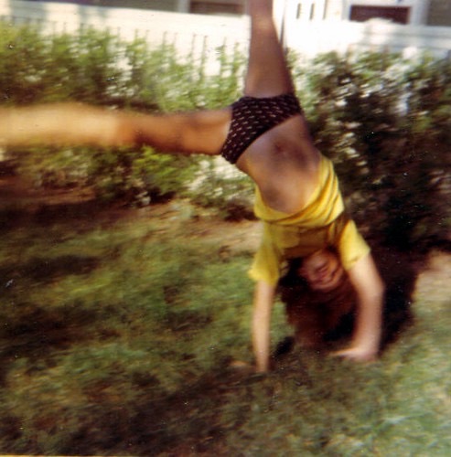 A young Rebecca doing a handstand in the yard · c. 1972