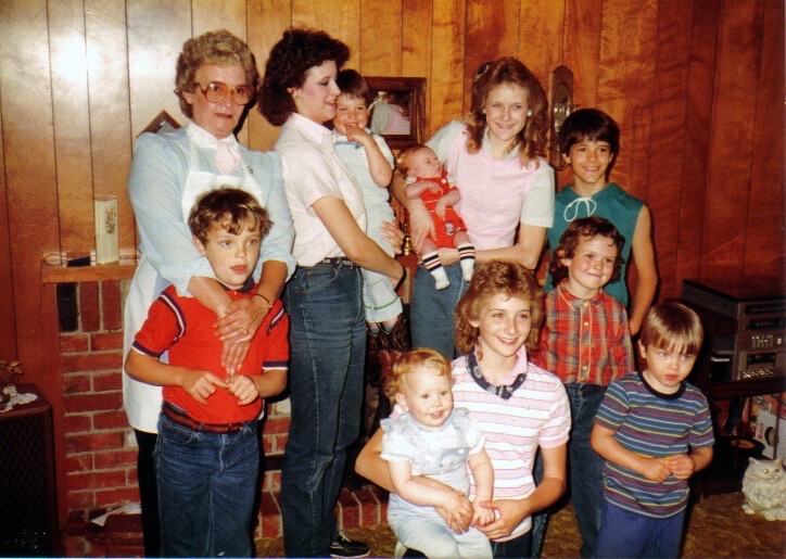 Young Garrett and his grandmother among a crowd of nieces and nephews at a family gathering · c. 1986